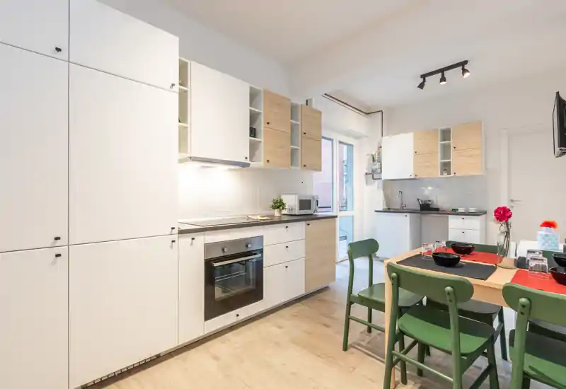 Contemporary, bright kitchen with integrated appliances, white and wood cabinets and a small dining table set for four — ideal for a compact city apartment.
