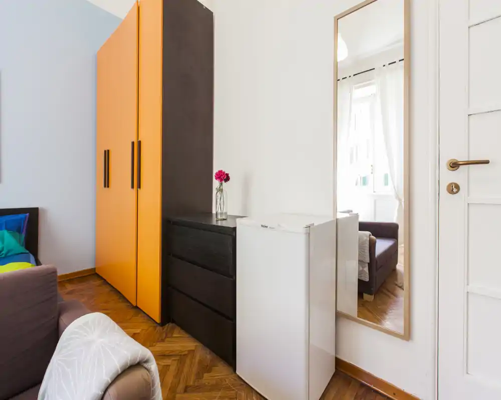Zona giorno luminosa e accogliente con un armadio colorato, comodi posti a sedere e pavimenti in legno caldo, perfetta per soggiorni brevi.