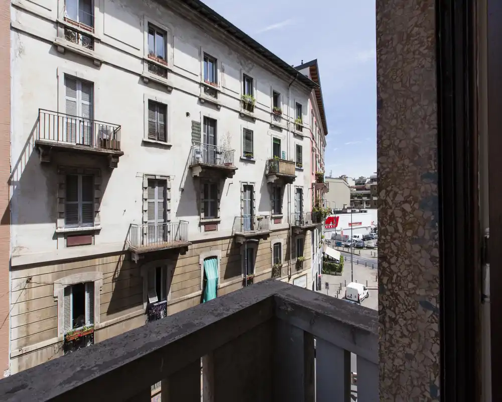 Piccolo balcone soleggiato con vista sulla strada cittadina e sull'edificio storico di fronte, perfetto per un caffè mattutino.