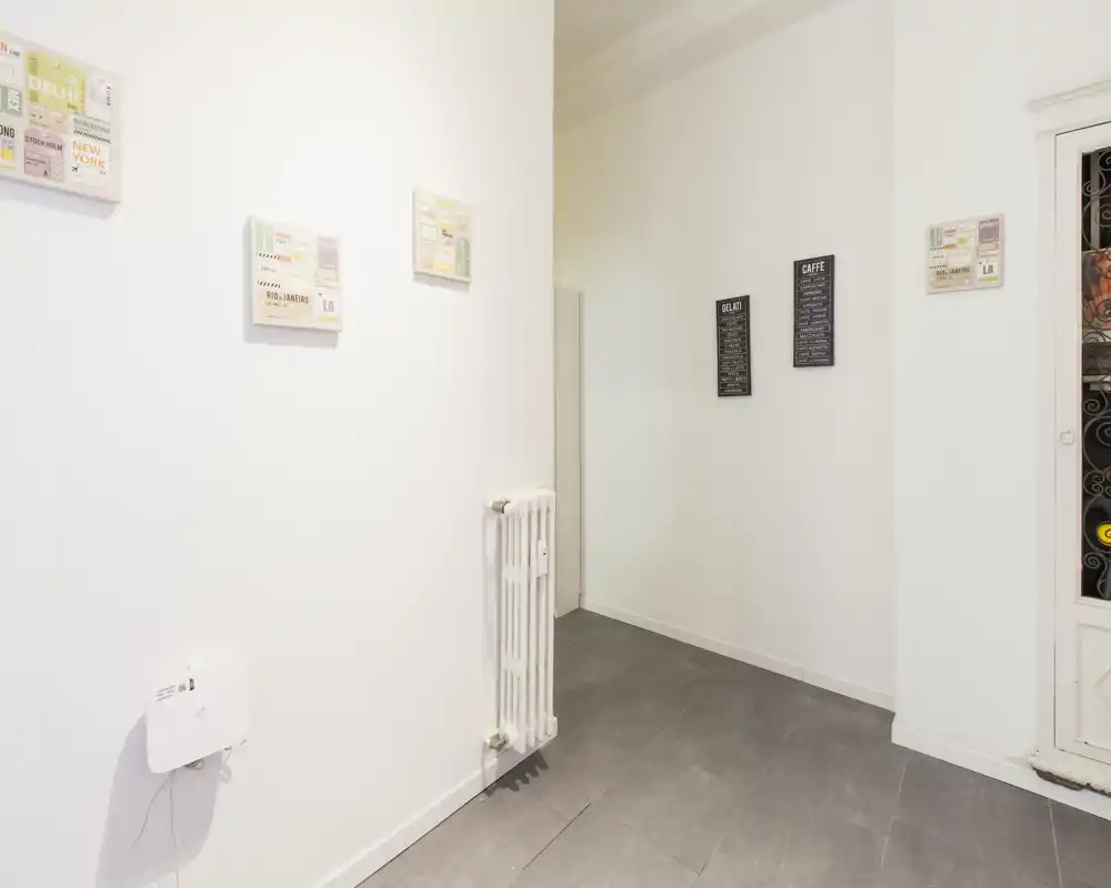 Ingresso semplice e luminoso con pareti bianche, pavimento piastrellato e un termosifone; pulito e minimal, adatto come corridoio d'ingresso.