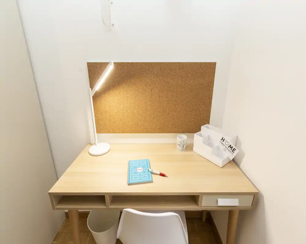Bright, tidy desk nook with a corkboard, lamp and small organizer — a compact workspace corner ideal for studying or remote work.