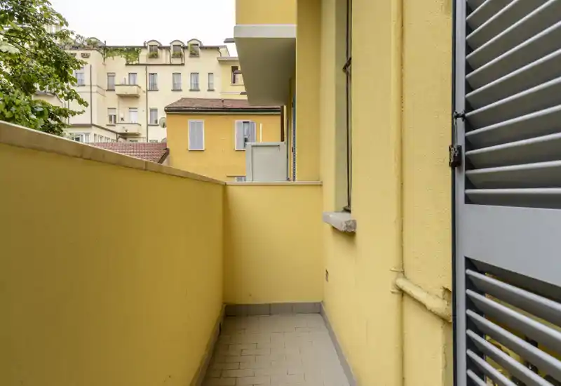 Small private balcony with yellow walls, tiled floor and city-facing views — ideal for a morning coffee or plants.