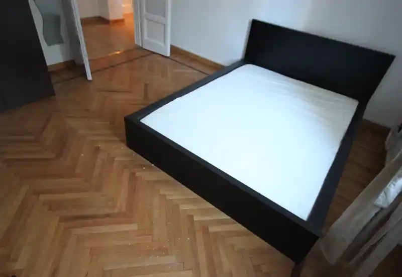 Camera da letto moderna e luminosa con letto matrimoniale a piattaforma nero e pavimento in parquet; stile minimalista e luce naturale.