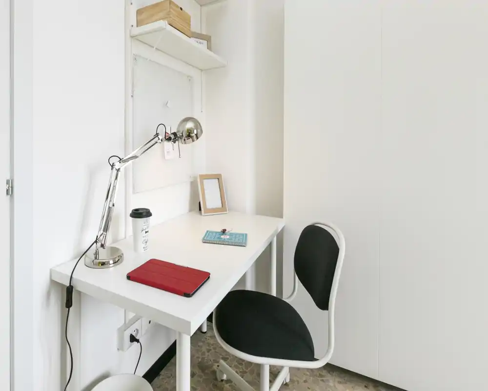 Bright, minimal workspace with a white desk, adjustable desk lamp and a supportive swivel chair — suitable for remote work or study.