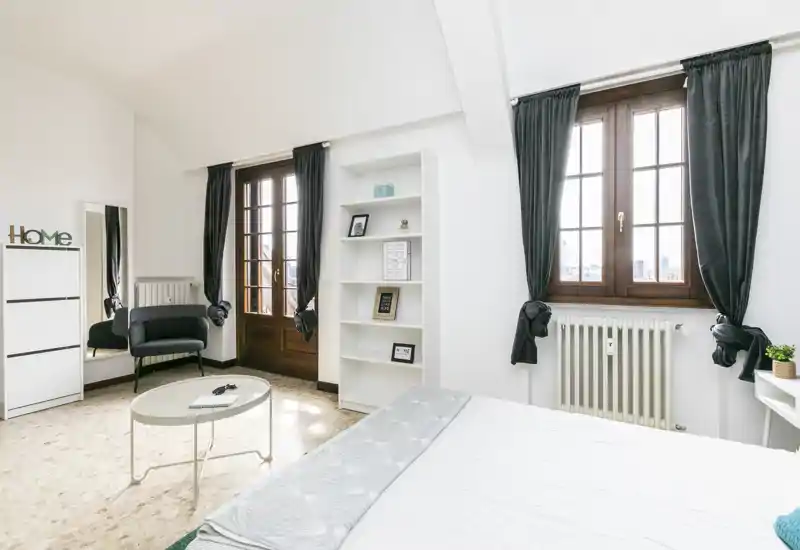 Bright, modern bedroom with large wooden-framed windows, a neatly made bed and minimal Scandinavian-style furniture creating an airy, welcoming space.