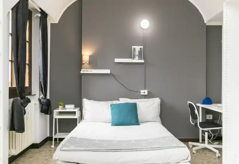 Bright, modern bedroom with a centrally placed double bed, cozy textiles and a small workspace to the side — ideal for a stylish short-term rental.
