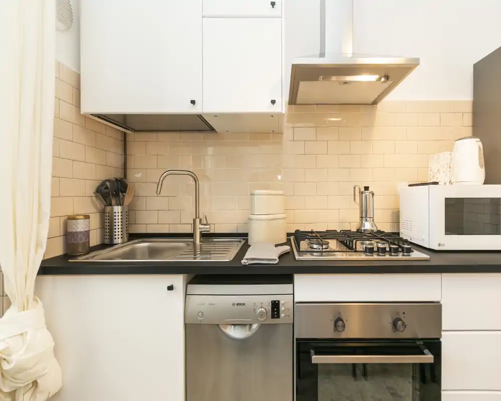 Bright, compact kitchen with stainless-steel appliances, gas hob, built-in oven and dishwasher, and tiled backsplash — neat styling ideal for rental listings.