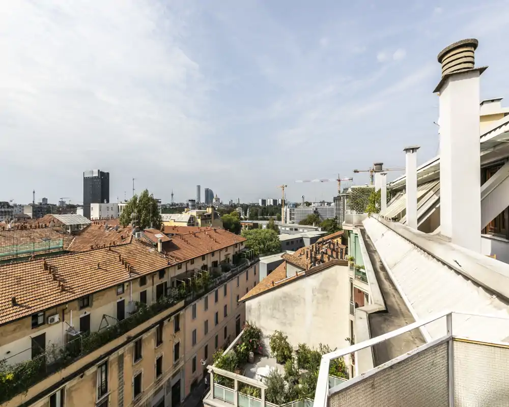 Sunny rooftop terrace view over terracotta rooftops and a distant city skyline — ideal for a morning coffee or relaxing outdoors.