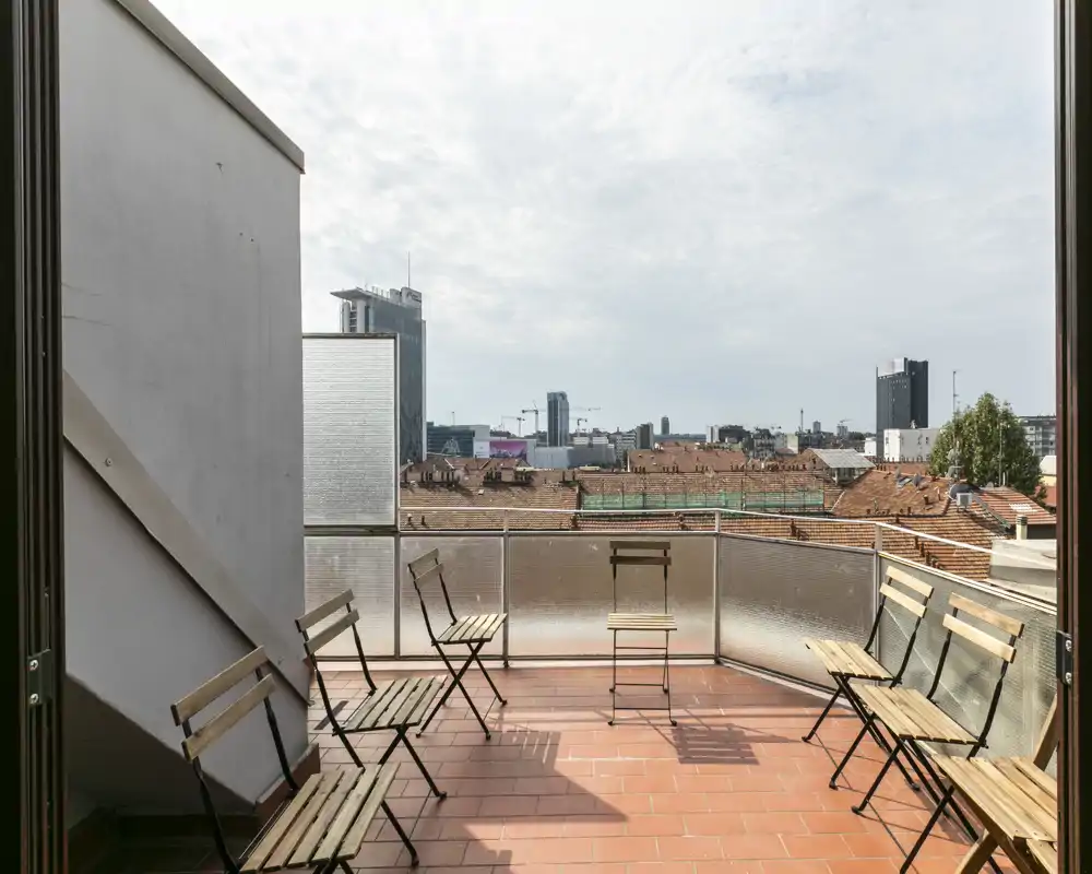 Sunny private terrace with folding chairs and a city skyline view — ideal for morning coffee or relaxing outdoors.