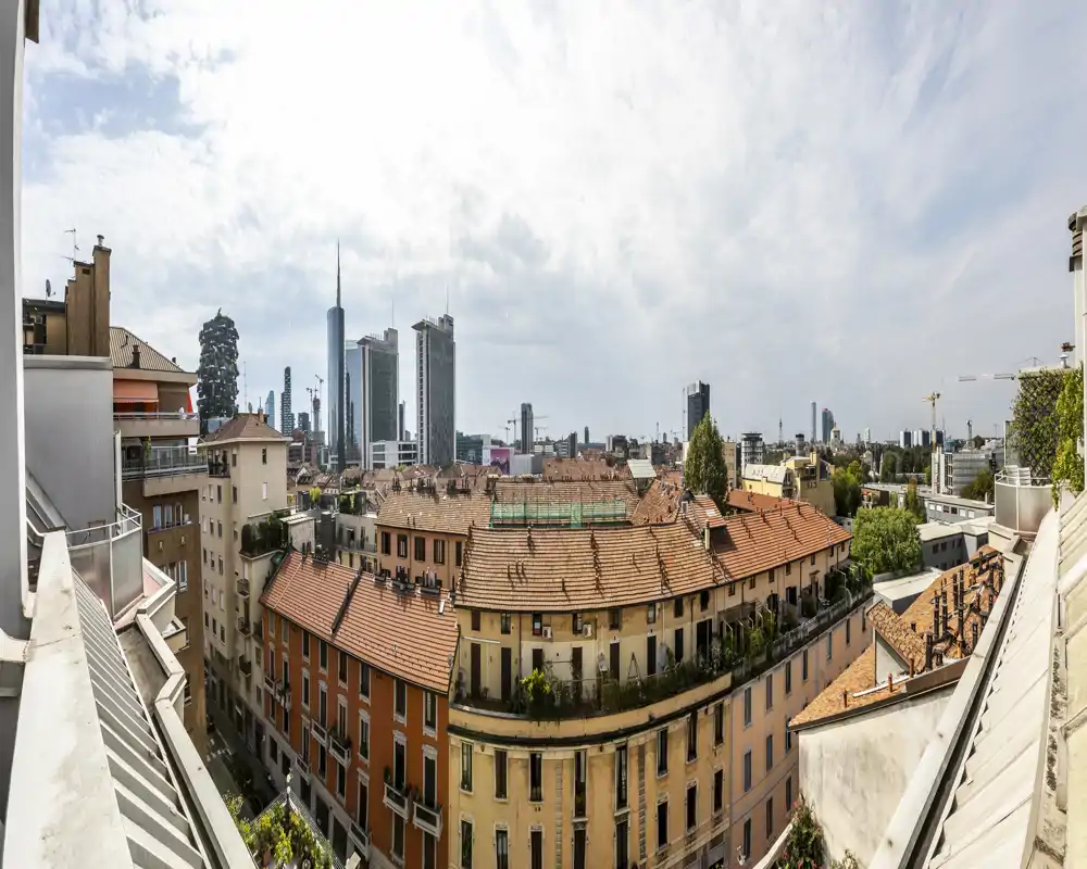 Panoramic balcony view over historic rooftops and a modern city skyline — bright daytime terrace perspective ideal for listing the outdoor aspect and city views.