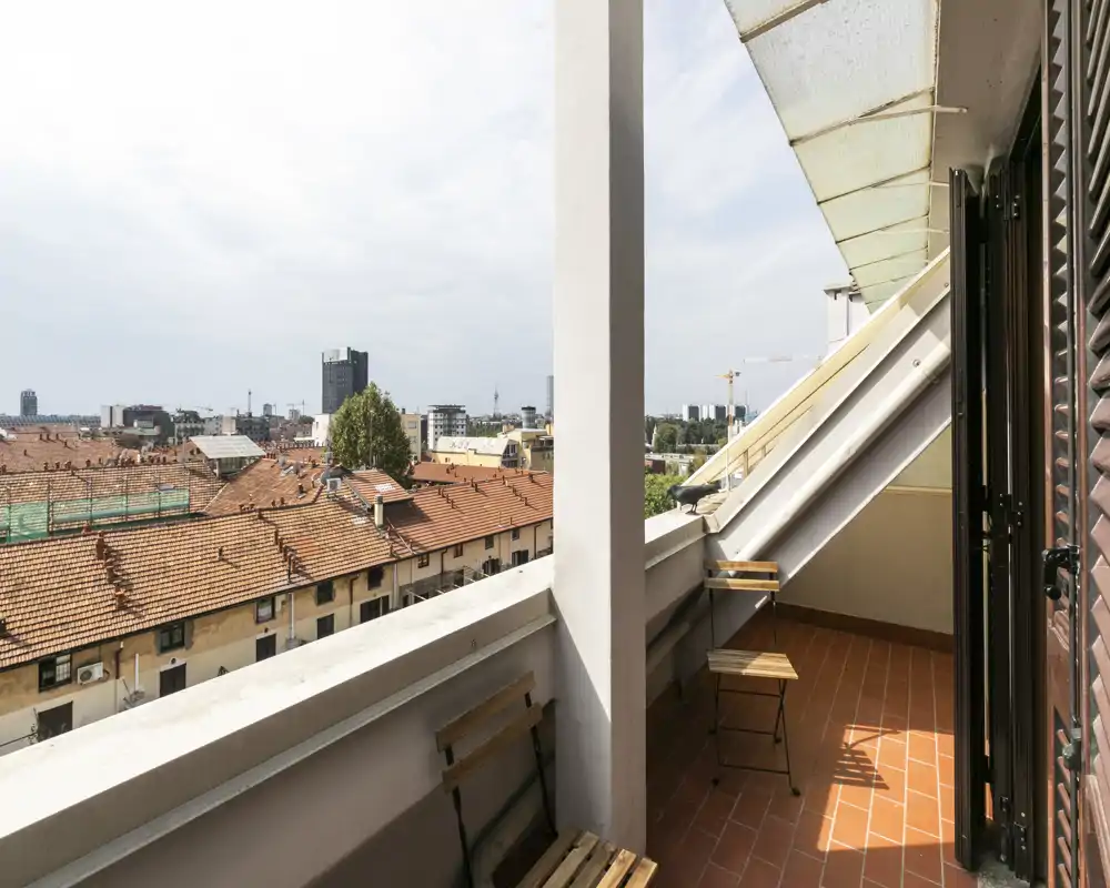 Sunny balcony with terracotta tiles, a small bistro set and city rooftop views — ideal for morning coffee.