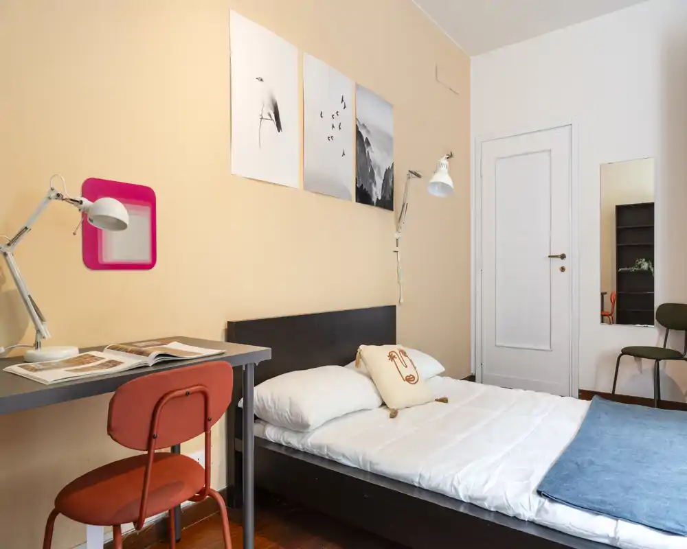 Dormitorio bien decorado con cama individual, escritorio y silla. Colores cálidos y buena luz natural que hacen la estancia luminosa y acogedora.