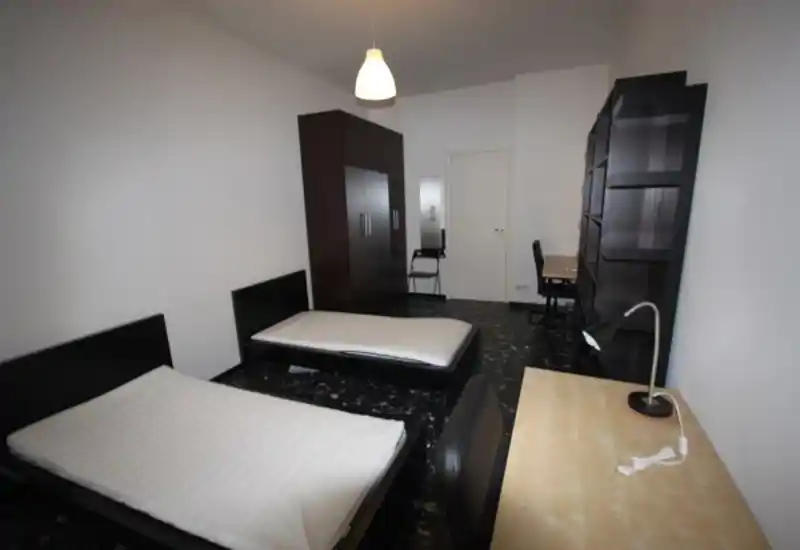 Amplia habitación con dos camas individuales, un gran armario, escritorio y estanterías — funcional y bien distribuida, perfecta para compañeros de piso o estudiantes.