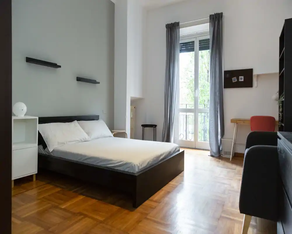 Camera da letto luminosa e minimal: letto matrimoniale, pavimento in parquet e ampia finestra che illumina l'ambiente, perfetta per annunci che puntano su ordine e tranquillità.