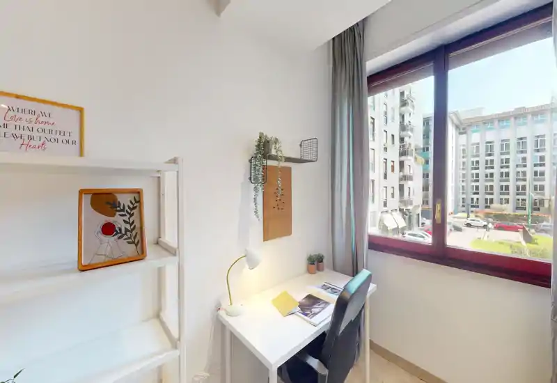 Bright study corner by a large window: compact desk with lamp, chair, small plants and shelving, ideal for remote work with city views.