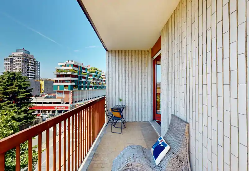 Sunny balcony with a wooden railing, tiled floor and a small bistro table with chairs — ideal for morning coffee and city views.