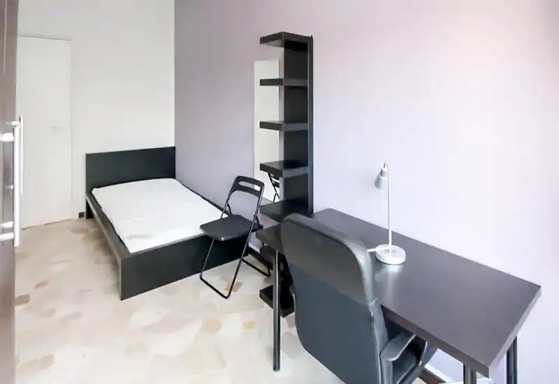 Dormitorio individual luminoso y minimalista con cama baja negra, escritorio y estanterías: espacio funcional y moderno, ideal para estudiante o ocupante individual.