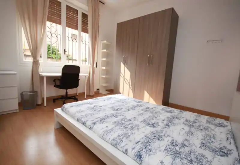 Bright, well-staged bedroom with a double bed, wardrobe and a desk by the window—ideal for both rest and study.