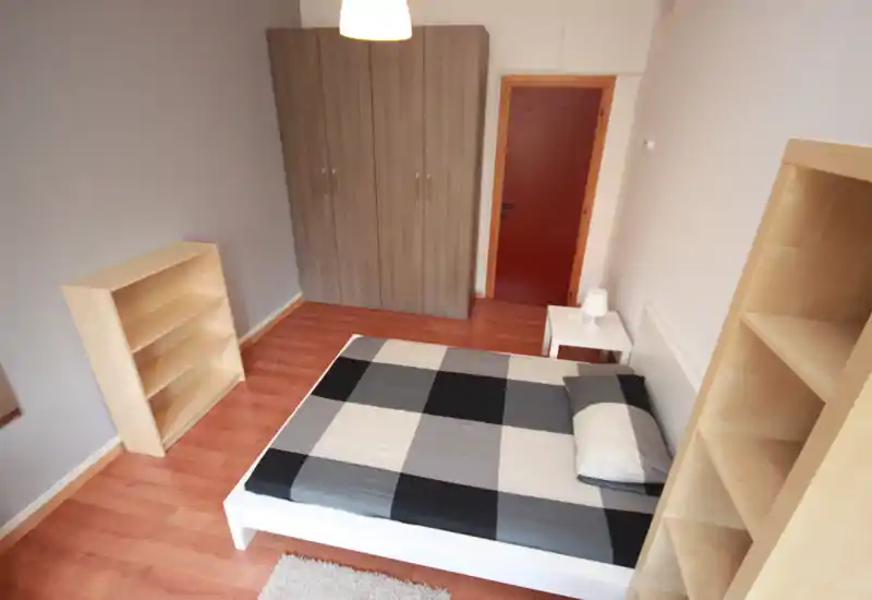 Bright, tidy bedroom with a double bed, bedside table and wardrobe; light wood floors and simple, modern furnishings make it welcoming for renters.
