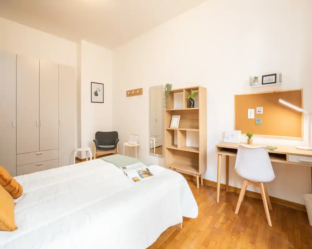 Dormitorio luminoso y bien presentado con cama doble, suelos de madera y una zona de escritorio práctica — ideal para estudiantes o profesionales.