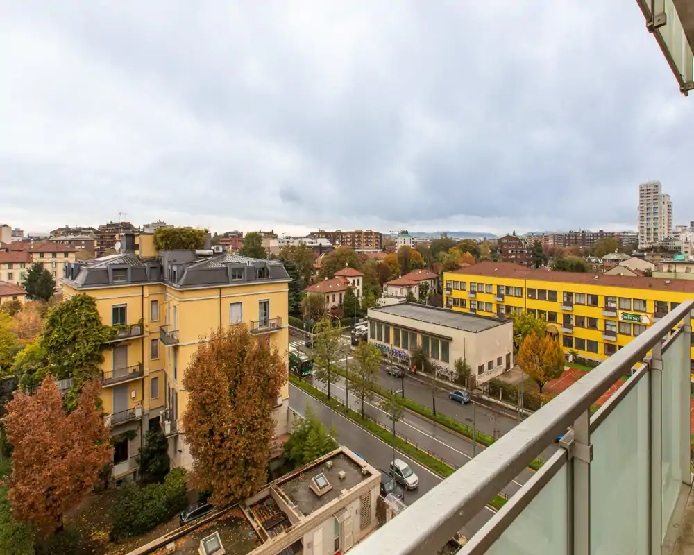 Balcony view overlooking a residential street with colorful buildings and autumn trees — ideal for morning coffee and city watching.