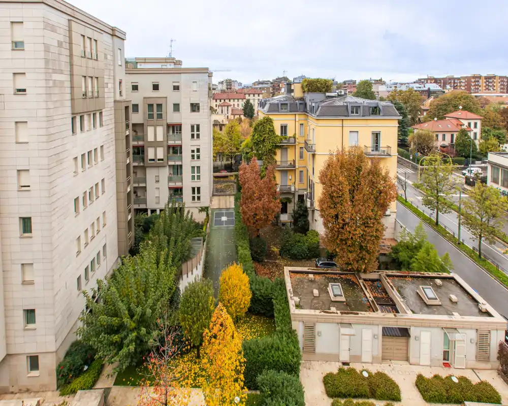 View of an inner courtyard and surrounding urban buildings with autumn trees and pathways — bright, clear outdoor space suitable for listings highlighting outdoor areas.
