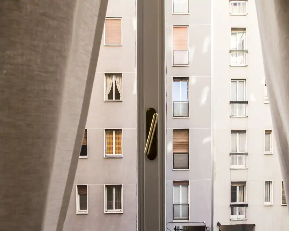 Vistas desde la ventana de un apartamento con las fachadas de edificios vecinos, enmarcadas por cortinas suaves.