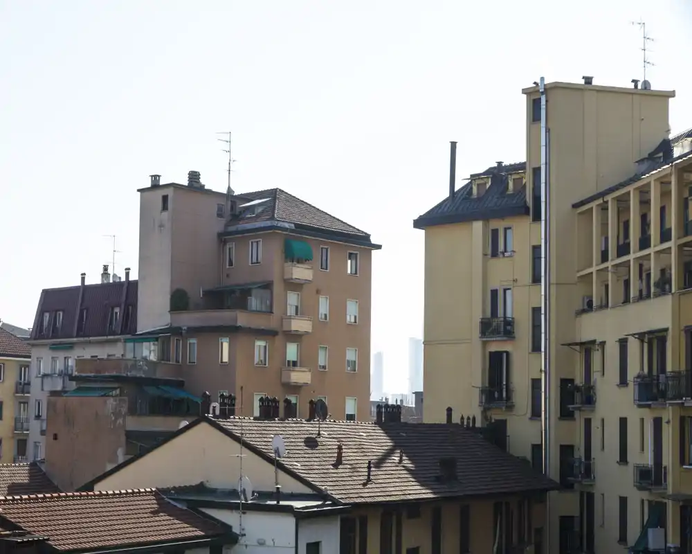Vue extérieure montrant des immeubles adjacents et des toits avec de petites terrasses et antennes, prises en plein jour clair.