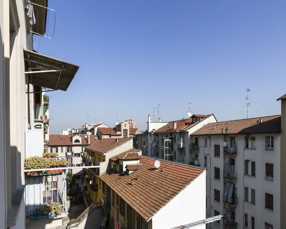 Vue ensoleillée depuis un balcon sur les toits des immeubles voisins avec antennes et ciel bleu — parfaite pour illustrer la luminosité extérieure et le contexte urbain.