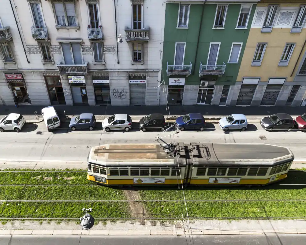 Vue extérieure d'une rue avec un tram jaune sur les rails, des voitures en stationnement et des façades d'immeubles — scène urbaine en plein air, pas une pièce intérieure.