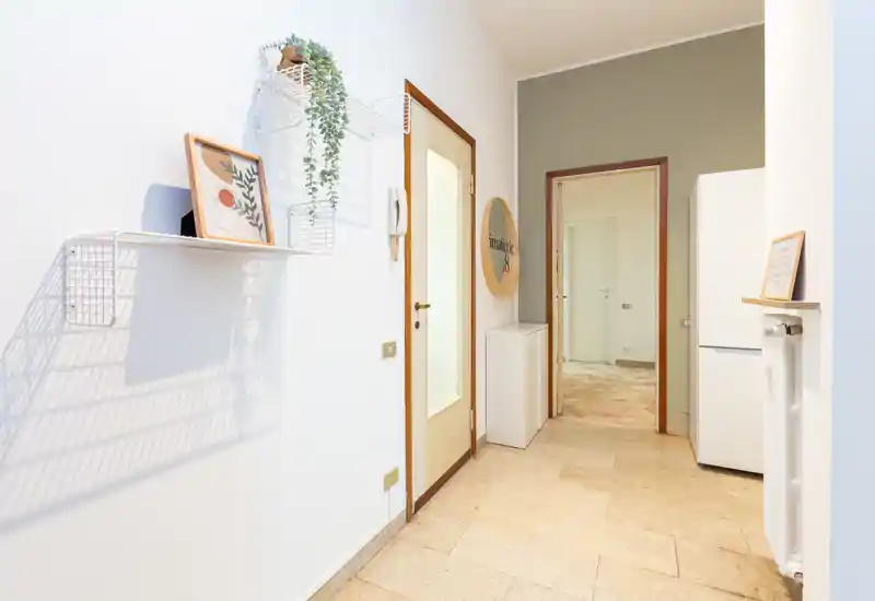 Entrée lumineuse bien éclairée avec sol carrelé, étagères murales et petit meuble de rangement — espace d'accueil propre et accueillant.