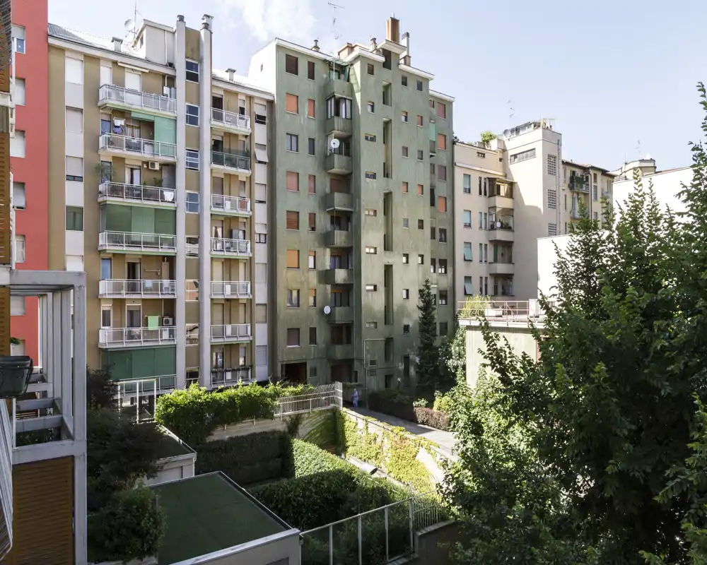 View of an inner courtyard and neighboring apartment façades with balconies and greenery — ideal to show building surroundings and natural light.