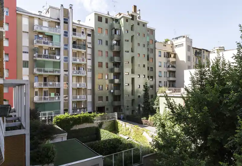 View of an inner courtyard and neighboring apartment façades with balconies and greenery — ideal to show building surroundings and natural light.