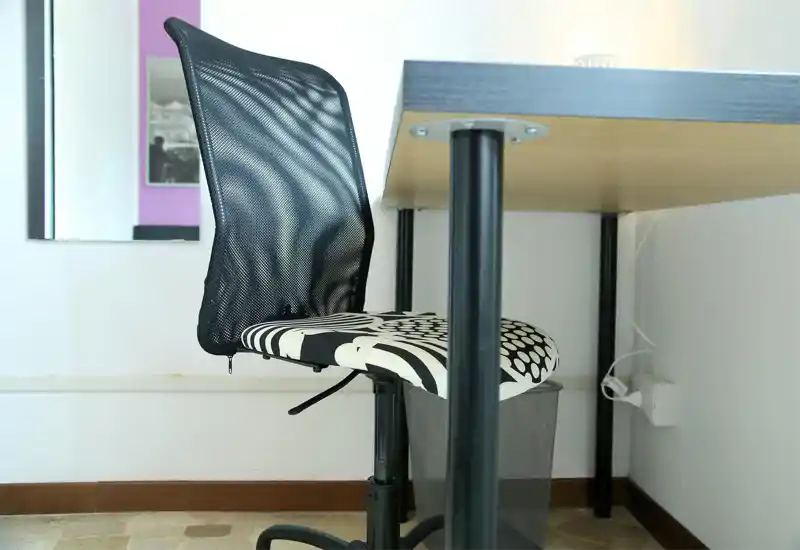 Simple workspace corner with a patterned swivel chair and a wooden desk. Clean, bright composition suitable for a study or home office listing.
