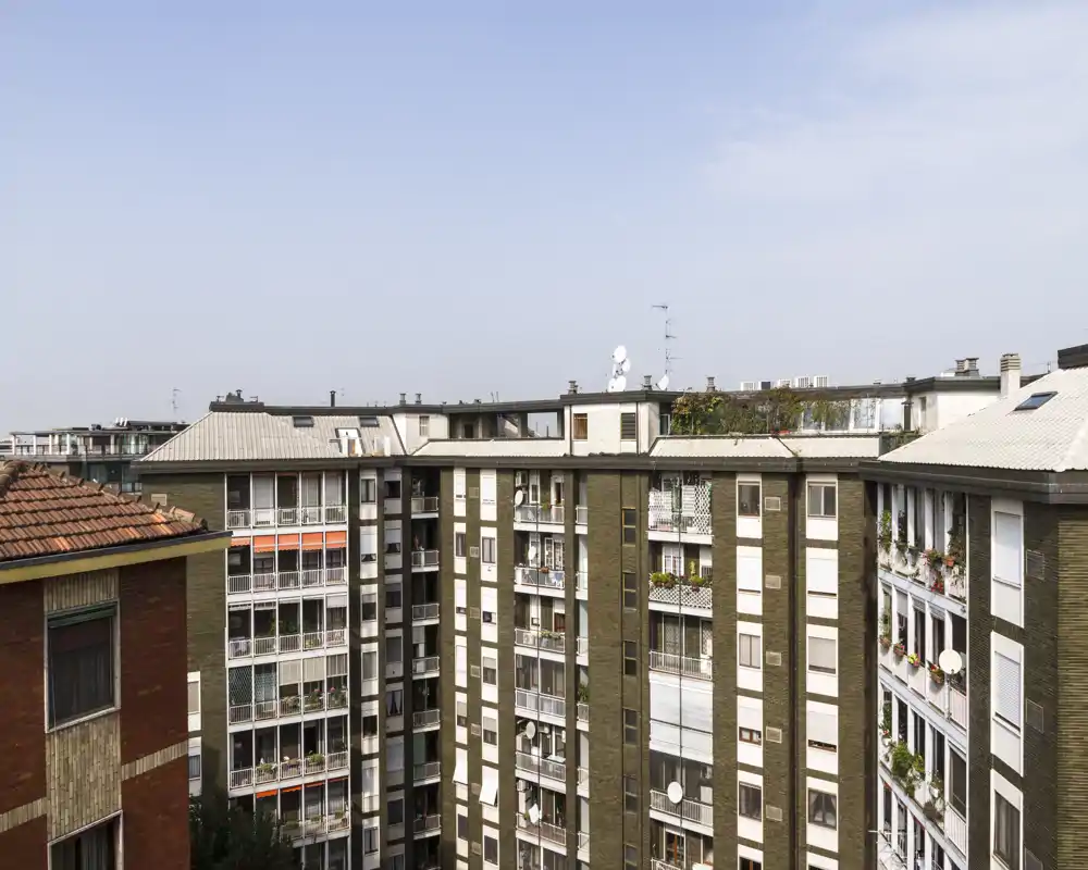Vista esterna sull'affaccio cittadino con facciate e balconi di un condominio sotto cielo limpido — utile per mostrare l'involucro dell'edificio e il contesto del quartiere.