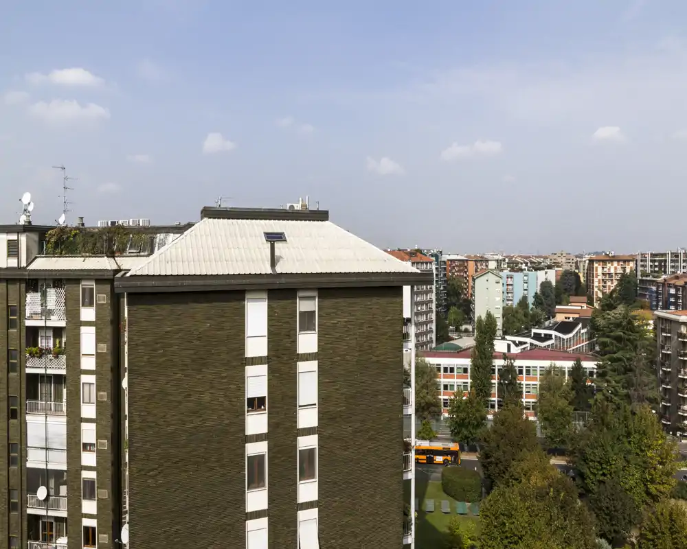 Urban exterior view showing neighboring apartment buildings, trees and a street — suitable as a city view or balcony shot highlighting surroundings.