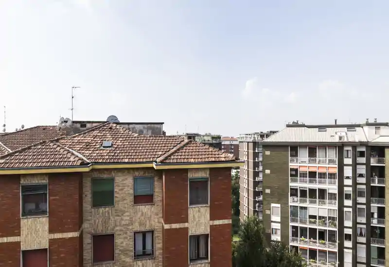 Urban exterior view showing neighboring apartment buildings and rooftops, suitable as a listing photo for a balcony or window view.