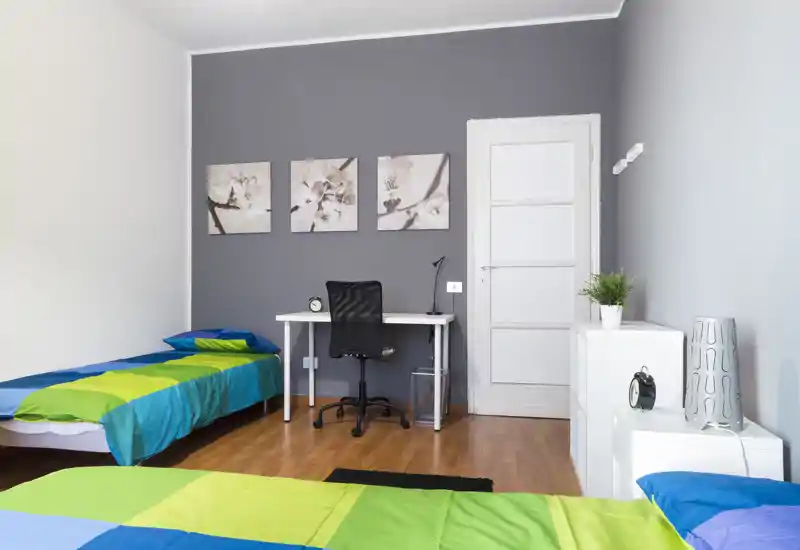 Bright, modern twin-bedroom with two single beds, a study desk and simple neutral decor — ideal for students or shared rentals.