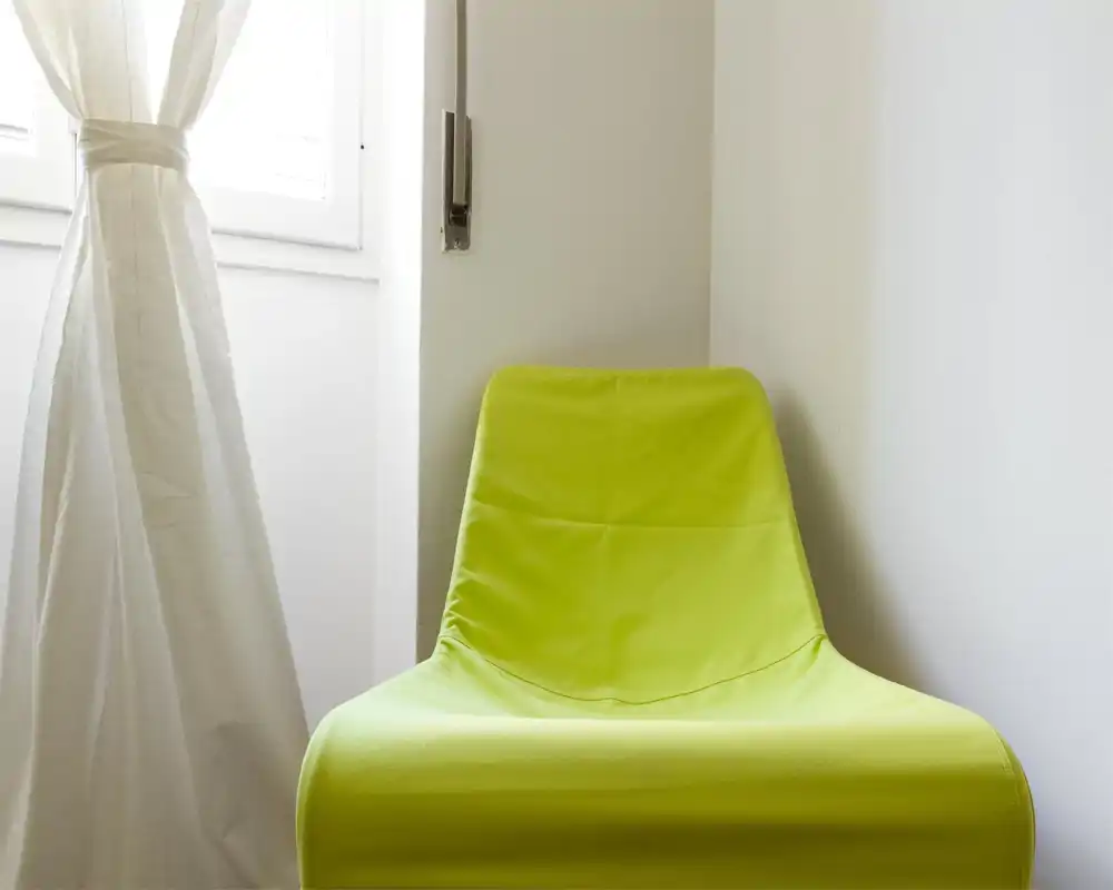 Coin minimaliste avec un fauteuil accent vert citron près d'une fenêtre lumineuse; style simple et moderne, parfait pour un coin lecture chaleureux.