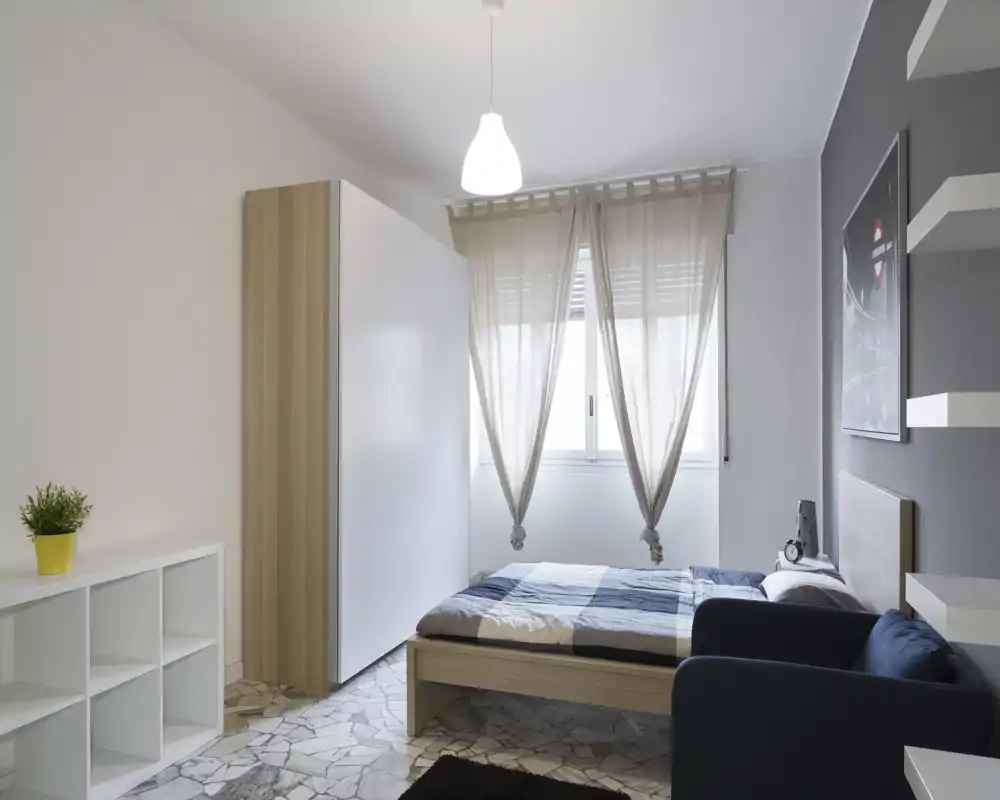 Bright, modern bedroom with a double bed next to a window, neutral decor and minimalist storage units for a clean, airy feel.