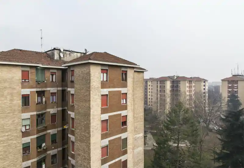 Exterior urban view showing apartment blocks and trees from a higher floor; neutral overcast lighting and clear building details.