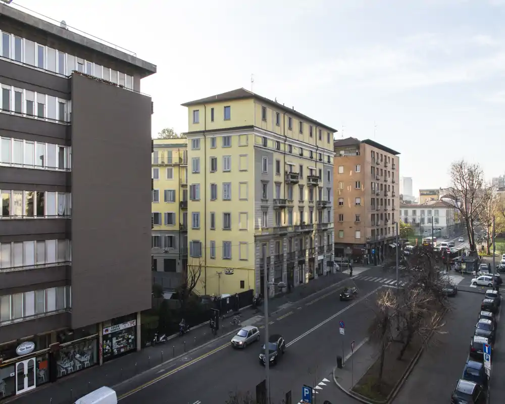 Veduta urbana dalla finestra di un piano superiore con edifici, auto parcheggiate e la strada: ideale per mostrare il quartiere e l'accesso stradale.