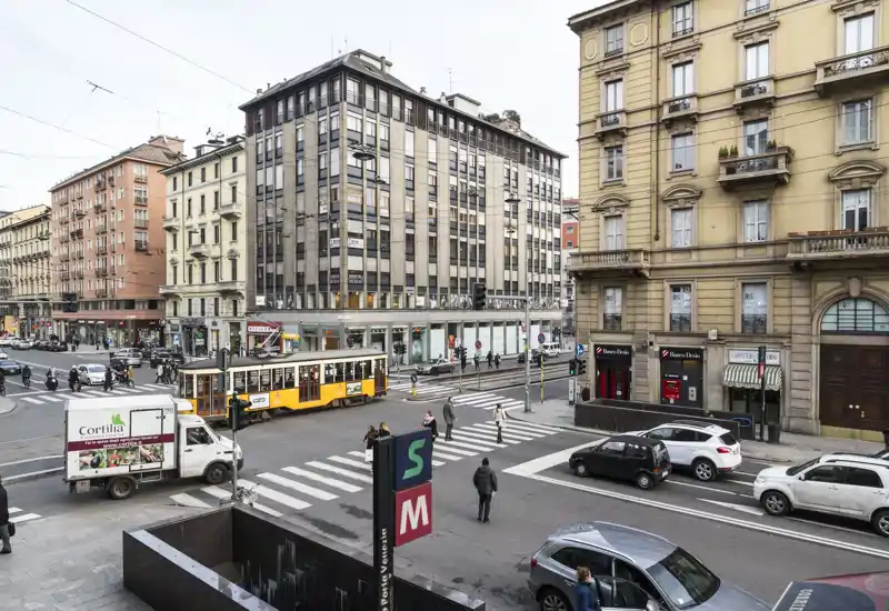 Bright urban street view showing a tram, pedestrian crossings and historic buildings — ideal to highlight proximity to public transport and city amenities.