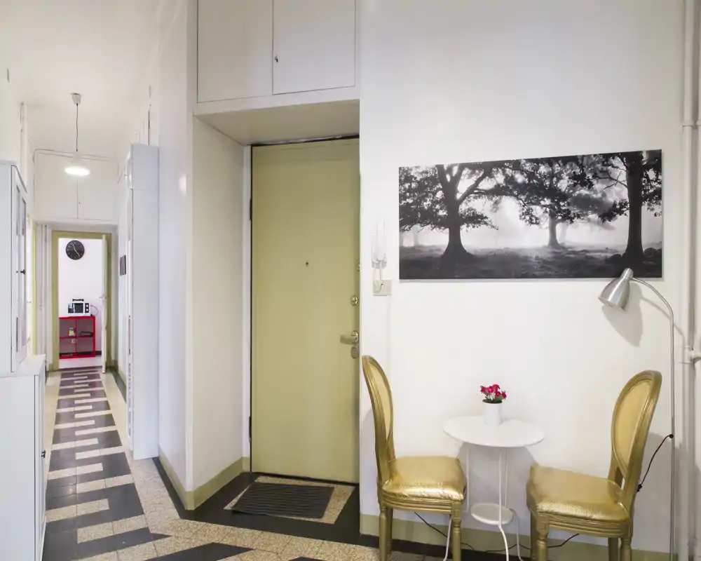 Bright and welcoming entrance hallway with a small bistro table and two chairs beside the main door; decorative wall art and patterned tile flooring create a stylish first impression.