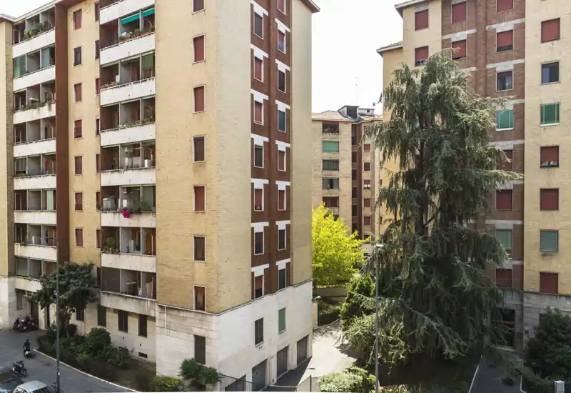 View of the apartment courtyard and surrounding residential buildings with mature trees and balconies — ideal to show building exterior and neighborhood context.