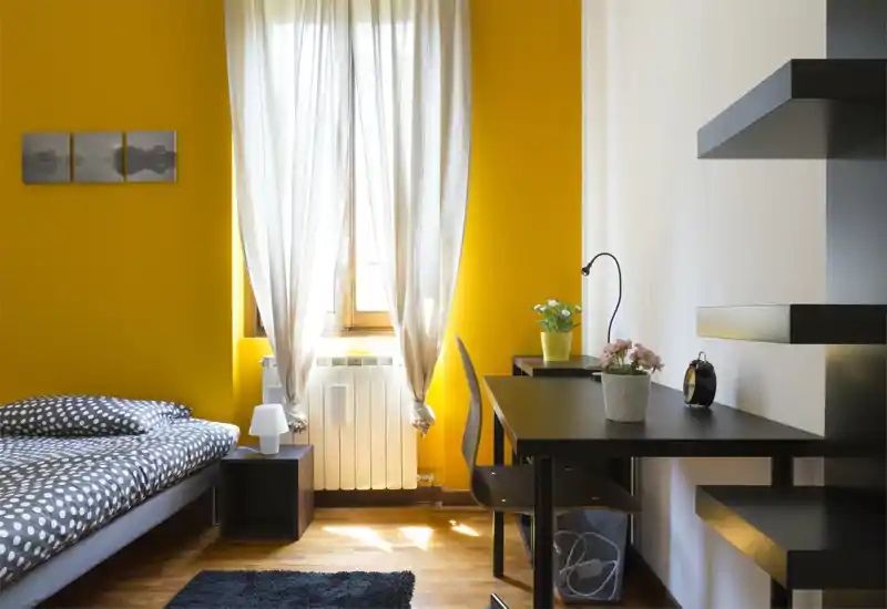 Dormitorio moderno y luminoso con cama de lunares, luz natural desde la ventana central y un escritorio ordenado — ideal para trabajar y relajarse.