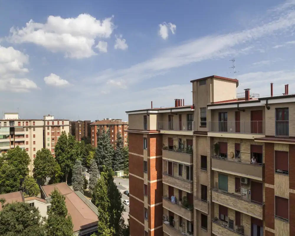 Vue urbaine lumineuse depuis un étage élevé montrant des immeubles résidentiels, des rues bordées d'arbres et un ciel dégagé — idéale pour mettre en valeur l'extérieur et le quartier.