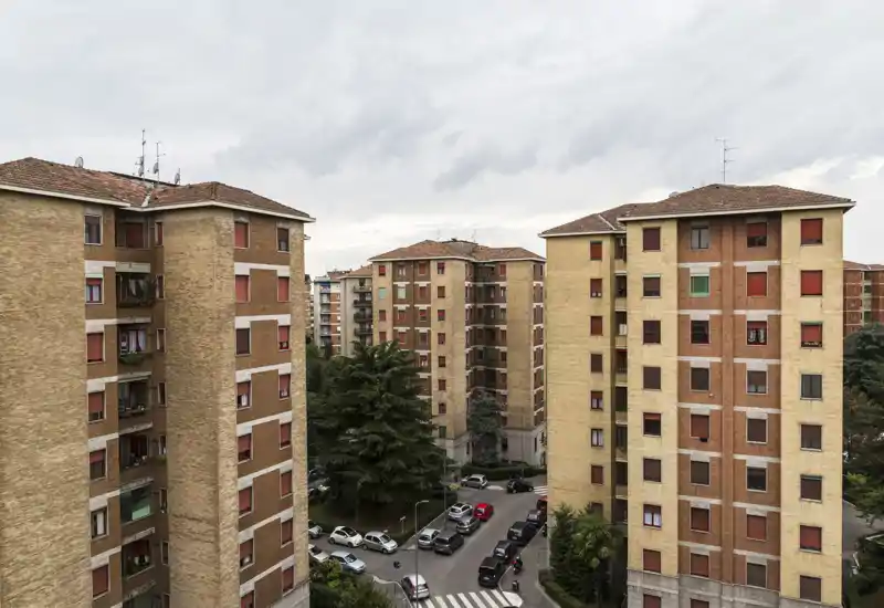 Vista exterior urbana con varios edificios residenciales, un patio con árboles y coches aparcados — adecuada como foto exterior para el anuncio.