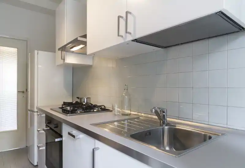 Modern, compact kitchen with stainless-steel sink, gas hob and built-in oven. Bright, clean surfaces and practical storage make it ideal for short-term rentals.
