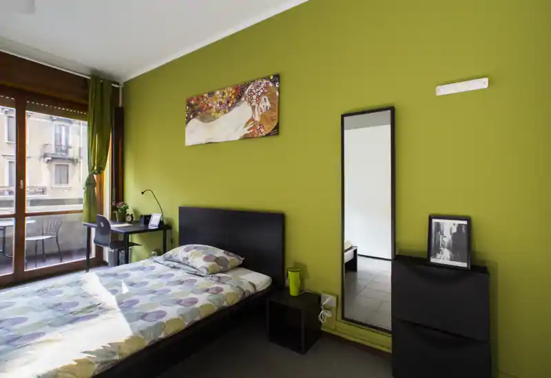 Habitación individual luminosa y moderna con cama cómoda, escritorio junto al balcón, espejo de cuerpo entero y decoración cuidada — ideal para estudiante o persona sola.